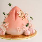 Light pink gradient muted 3D Longevity Peach Cake (Shou Tao cake) with edible sugar plum blossoms and mini fondant peaches