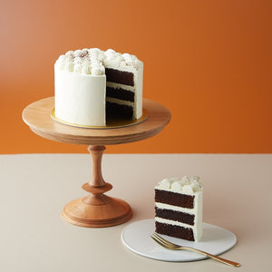 
                  
                    Load image into Gallery viewer, An earl grey lavender cake with a slice ut out of it to show the cross section. The slice is clean and neat, and the cake is a dark brown. It looks rich and moist. The cake has a white buttercream coating, and there are some earl grey tea leaves sprinkled on top.
                  
                
