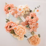 A light, dusty blue buttercream cake with pink and coral buttercream flowers on top, along with green edible wafer leaves. The flowers are assorted and realistic.