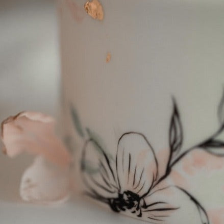 
                  
                    Load image into Gallery viewer, A close up of the cake, that focuses on a light pink edible wafer flower, and hand painted black outline of a flower.
                  
                