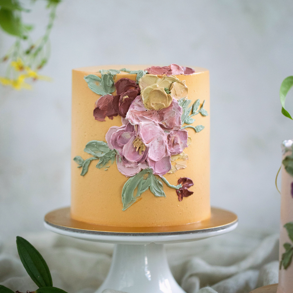 
                  
                    Load image into Gallery viewer, A pastel orange buttercream cake with red and pink palette knife buttercream flowers.
                  
                