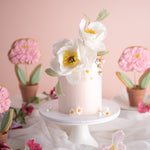 Light pink buttercream cake with beautiful realistic edible sugar peony flowers and leaves.