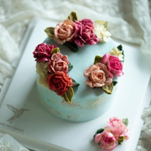 
                  
                    Load image into Gallery viewer, A light blue buttercream cake with light pink, dark pink and red buttercream roses on top. The cake also has accents of white.
                  
                
