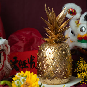 
                  
                    Load image into Gallery viewer, A golden cake that has been carved into the shape of a pineapple, with gold fondant pineapple stem. The cake is very realistic.
                  
                