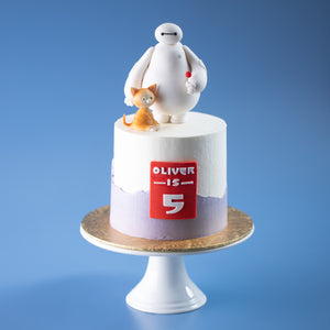 
                  
                    Load image into Gallery viewer, A cake with a white buttercream base, with a jagged light purple buttercream at the bottom half of the cake. The cake has a red fondant rectangle in the middle with the Big Hero 6 font. The cake is in Baymax&amp;#39;s armour colours. At the top of the cake there is a 3D fondant Baymax holding his signature red lolipop. To his right, there is an orange cat sitting by his feet.
                  
                