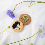 Two shortbread cookies, one lighter and one darker, with edible flowers pressed into the cookie. They are very pretty and look both delicate and delicious.