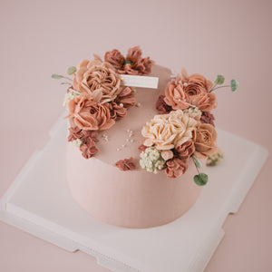 
                  
                    Load image into Gallery viewer, A light pink. buttercream base, with pink, beige and ivory buttercream flowers on top in a wreath style.
                  
                