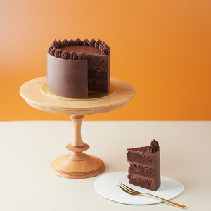 
                  
                    Load image into Gallery viewer, A chocolate cake with a slice cut out from it to show the cross section. The chocolate cake looks rich and moist, and it is coated in chocolate ganache.
                  
                