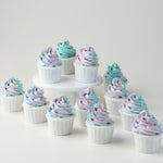 Multiple cupcakes with tall swirls of blue and purple ombre buttercream. The cupcakes have orange sprinkles on them for slight contrast.