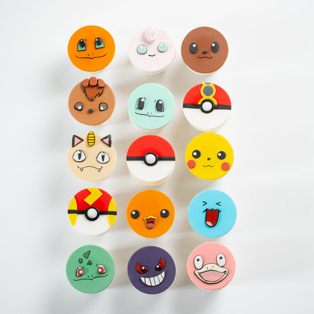 Cupcakes that have round fondant toppers that look like different pokemon. Three of them are types of Pokeballs. The pomemon faces are all extremely cute and true to the anime.