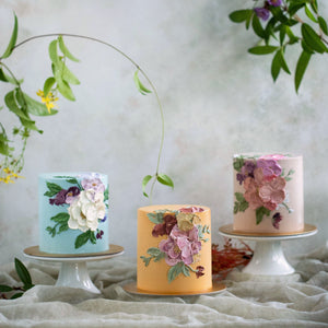 
                  
                    Load image into Gallery viewer, Three cakes in different colours with buttercream flowers adorning them.
                  
                